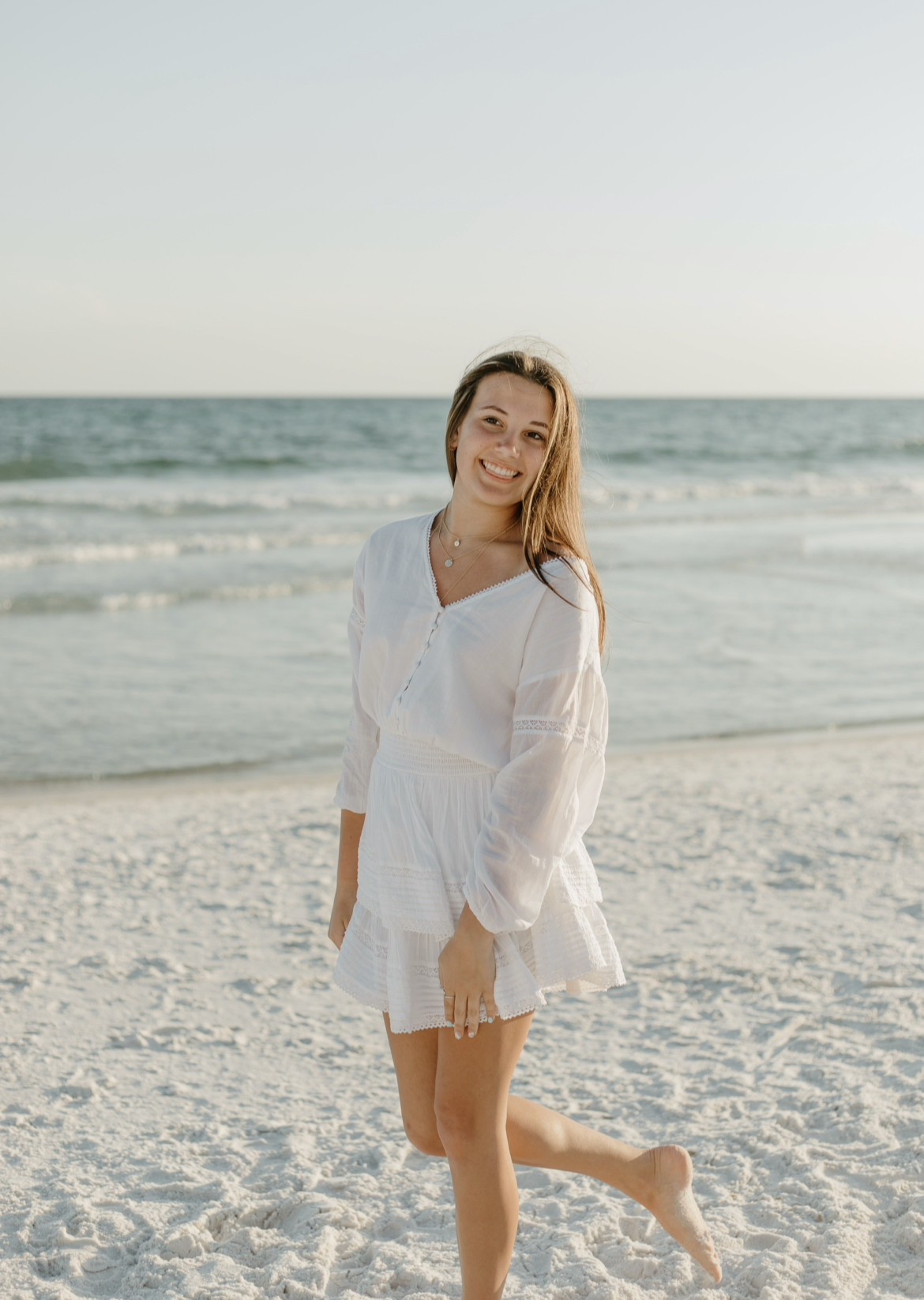 A person in a white dress on a beachDescription automatically generated