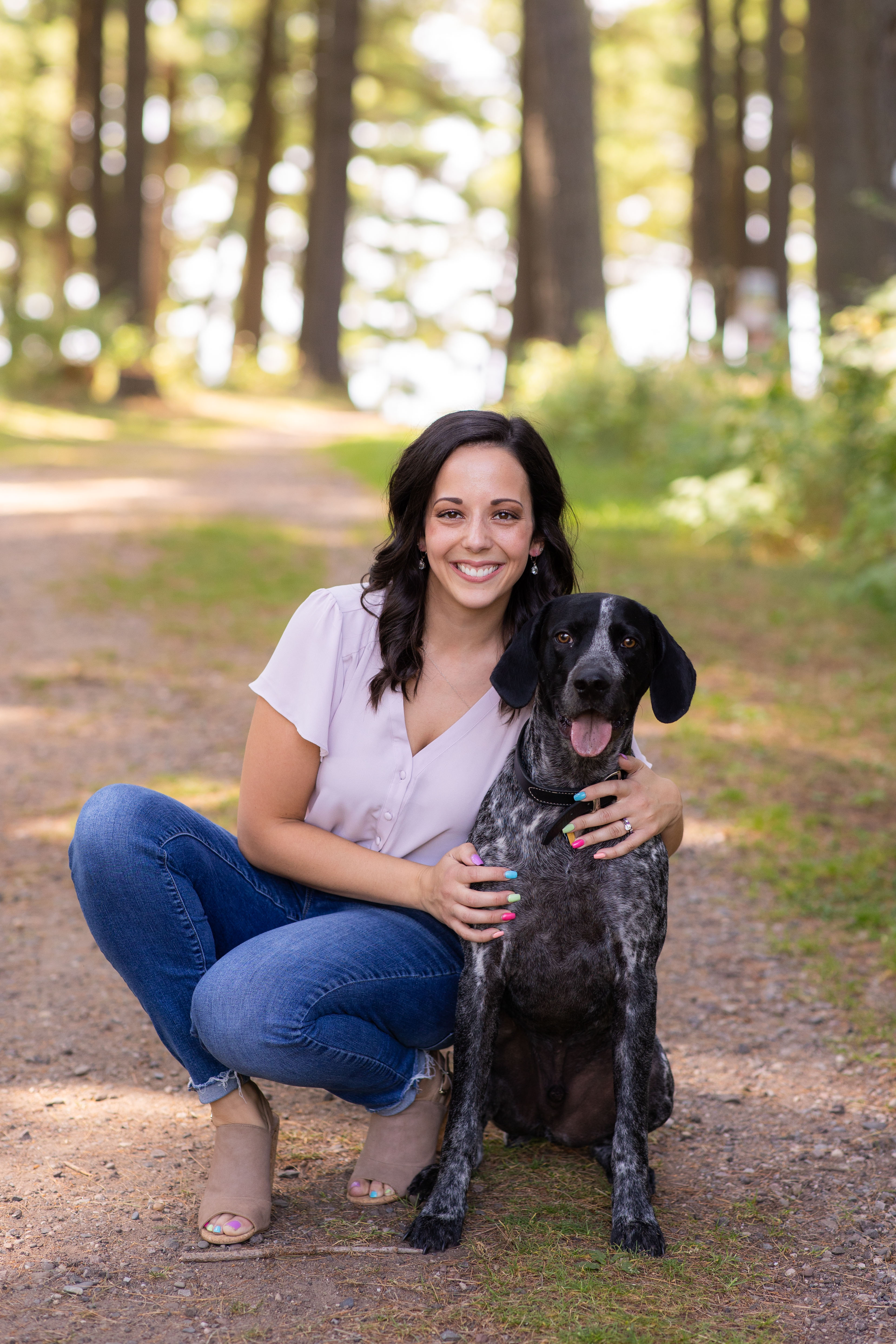 A person sitting on a dirt path with a dogDescription automatically generated